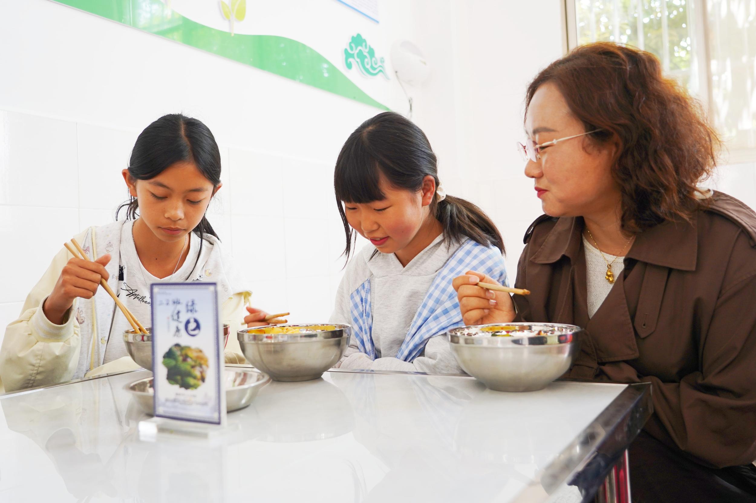 老师和孩子一同用餐。段雄瑞 摄